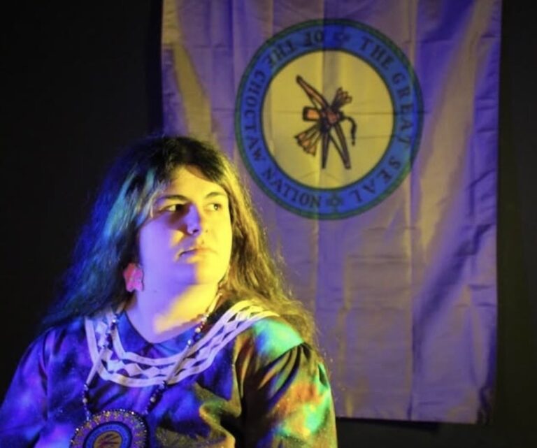 Portrait of Laika M. Taddei in front of a Choctaw Nation flag.